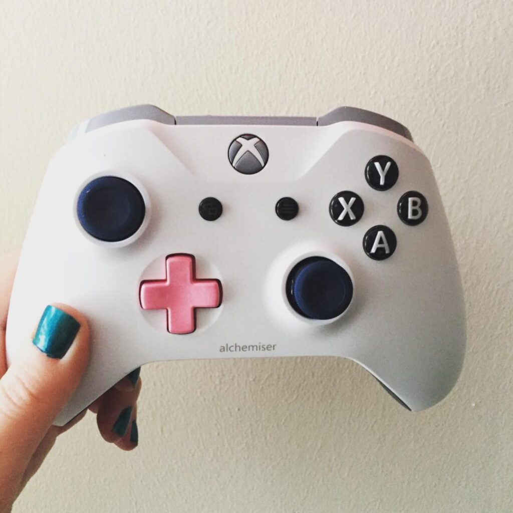Xbox video game controller, white with pink d-pad and "alchemiser" engraving